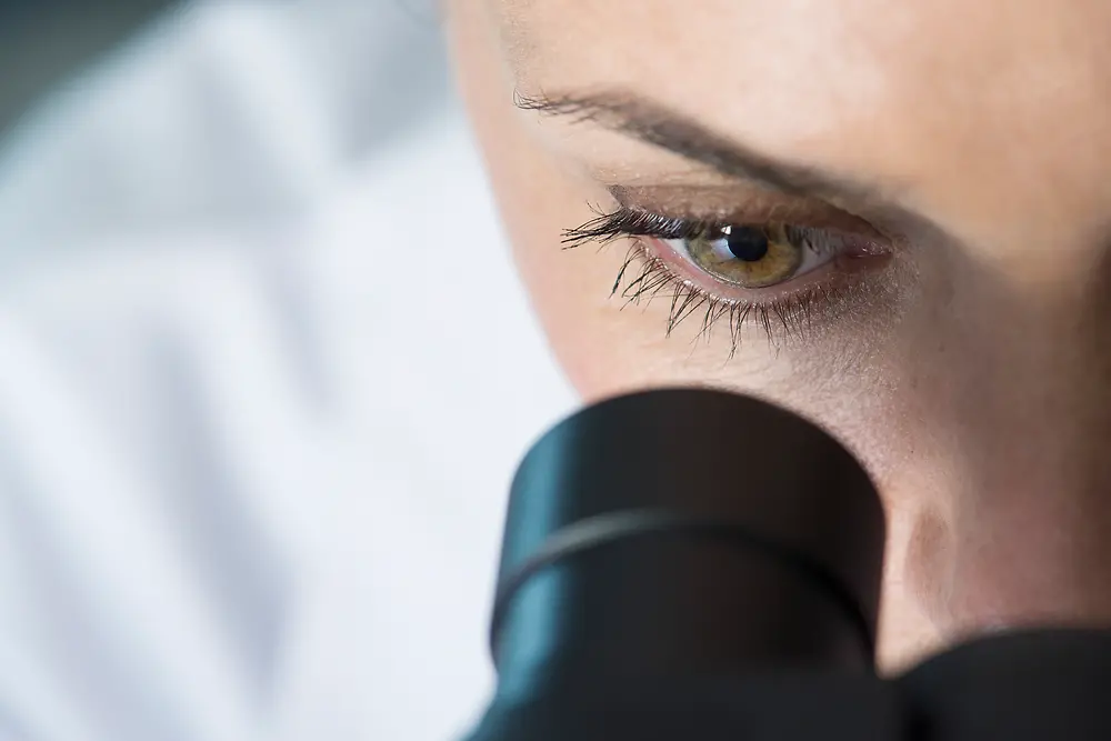 Ochiul unei femei care se uită la microscop