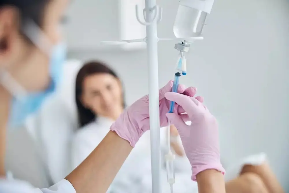 Profesionist medical care ține o pungă de perfuzie intravenoasă într-un cadru medical.